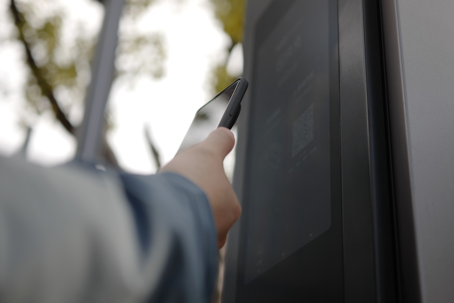 driver holds phone near ev charging station to scan a qr code to begin a charging session